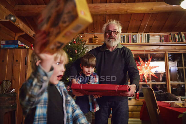 Fröhlicher Junge hält Weihnachtsgeschenk hoch — Stockfoto