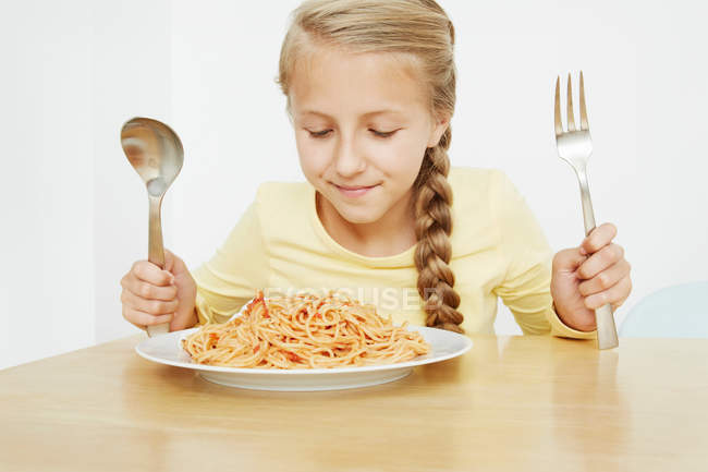 Fille avec assiette de spaghettis et couverts surdimensionnés — Photo de stock