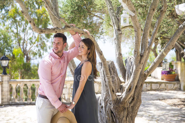 Couple by olive tree in boutique hotel garden, Majorca, Spain — Stock Photo