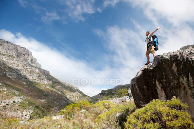 Чоловічий пішохід, що стоїть на скелі з розтягнутими руками — стокове фото