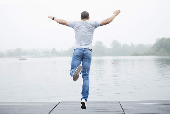 Молодой человек прыгает в озеро — стоковое фото