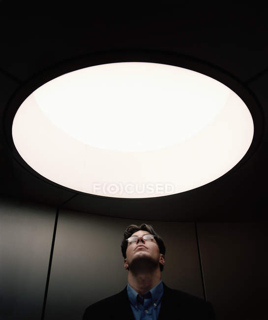 Portrait d'un homme adulte regardant à travers une fenêtre circulaire au plafond — Photo de stock
