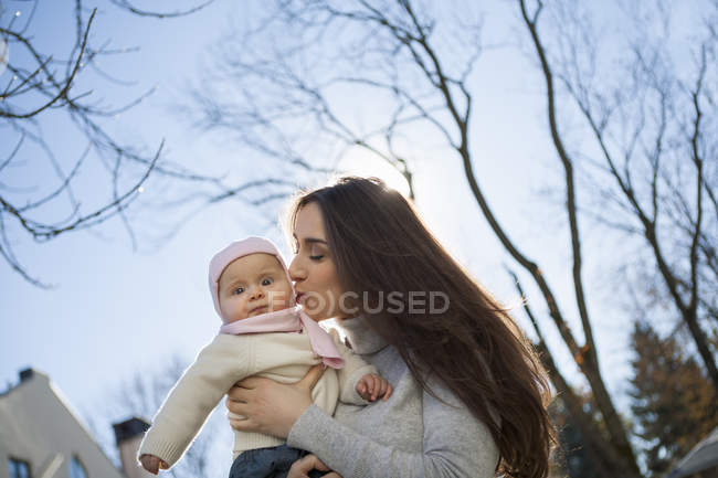 Mère embrassant bébé dans les bras — Photo de stock