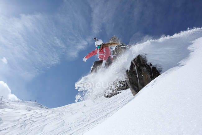 Молода жінка сноубордист зістрибнути з уступу на горі, Хінтертукс, Тіроль, Австрія — стокове фото