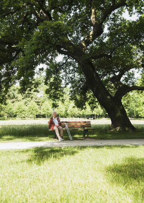 Seniorin sitzt auf Parkbank im Park — Stockfoto