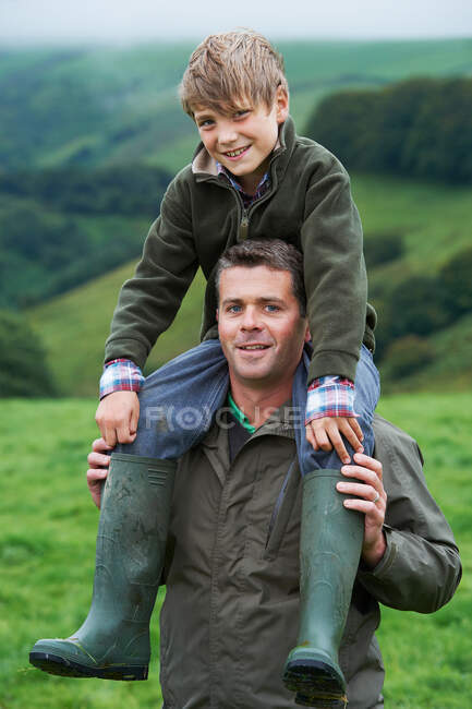 Père donnant un cochon à son fils dans le champ — Photo de stock