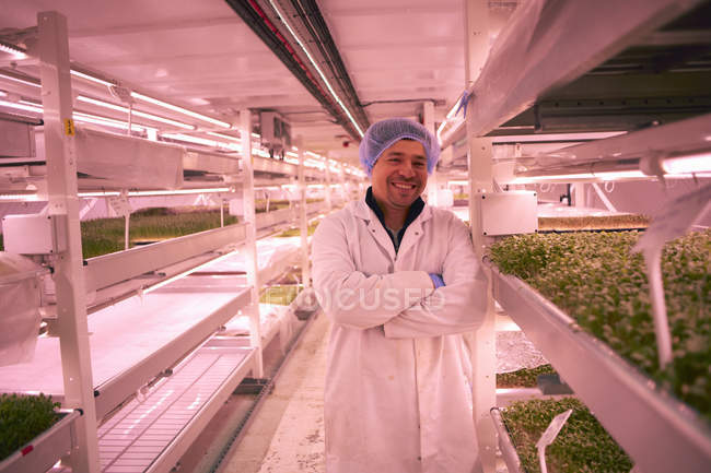 Worker wearing overall and hairnet looking at camera, arms crossed smiling — Stock Photo