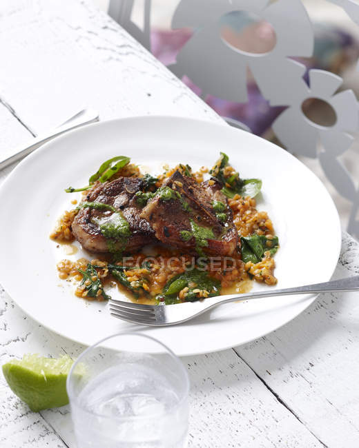 Plate of red lentils with lamb chops and herb garnish — Stock Photo
