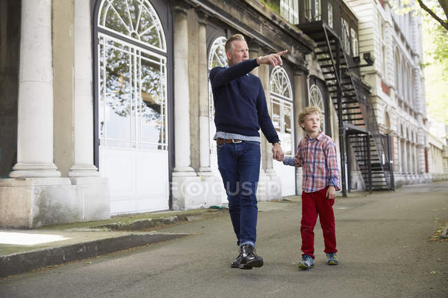 Vater und Sohn Händchen haltend und auf der Straße gehend, Vater zeigend, London, Großbritannien — Stockfoto