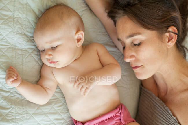 Madre y bebé que duermen en la cama - foto de stock