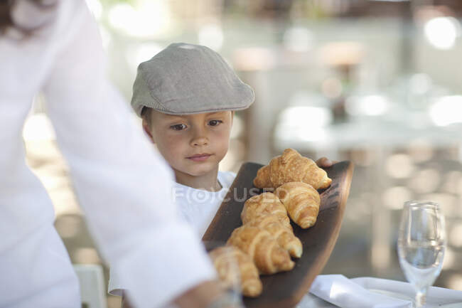 Junge serviert Platte mit Croissant — Stockfoto