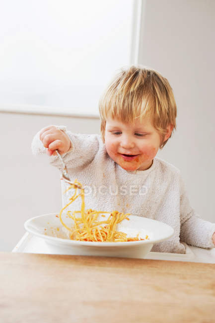 Happy baby boy eating spaghetti — Stock Photo