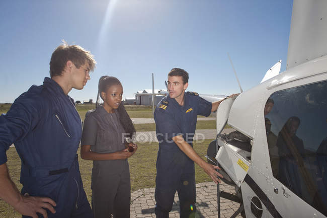 Flight instructor showing student pilots engine of helicopter — Stock Photo