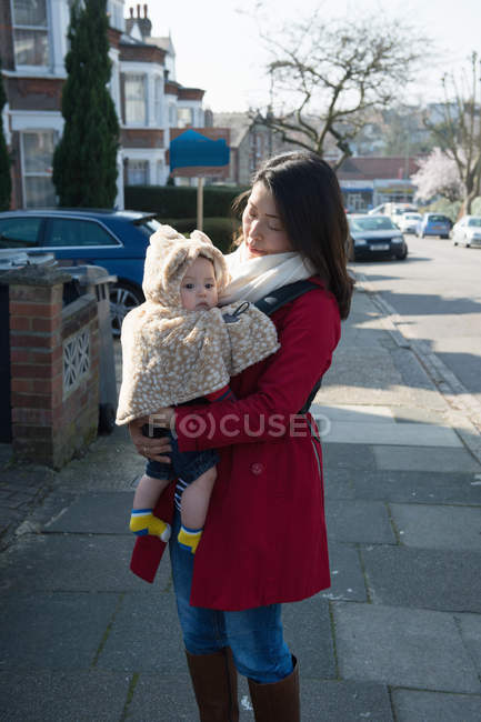 Mother walking outdoors, carrying baby boy in arms — Stock Photo