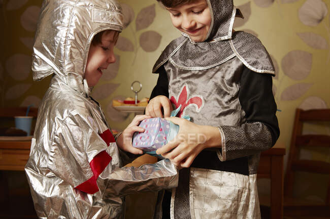 Два мальчика, одетые как рыцари, один получает подарок на день рождения — стоковое фото