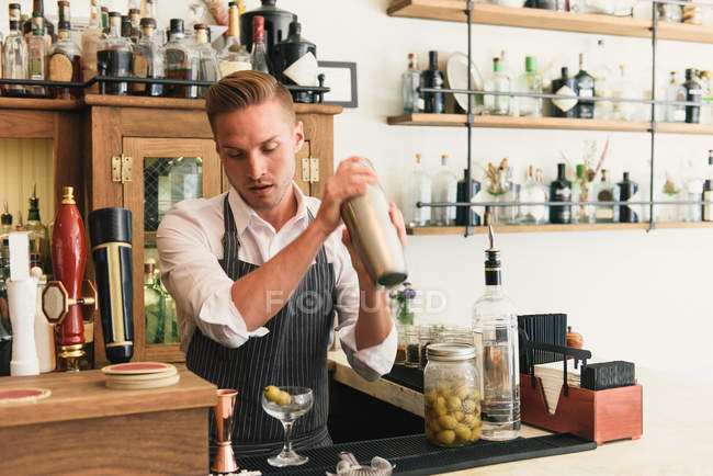 Bartender shaking cocktail shaker in cocktail bar — Stock Photo