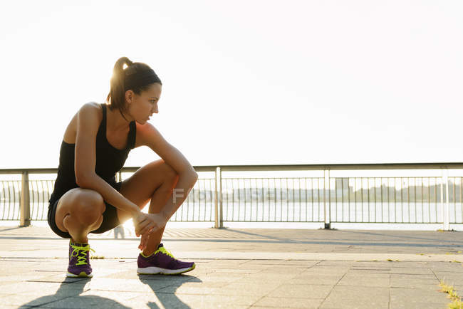 Young female jogger crouching and out of breath — Stock Photo