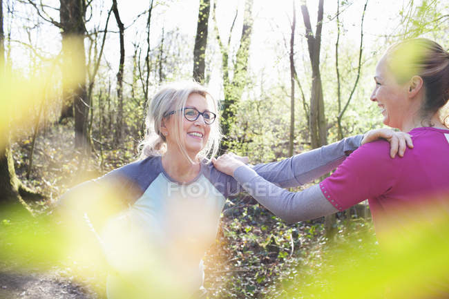 Women in forest, hand on each others shoulders stretching — Stock Photo