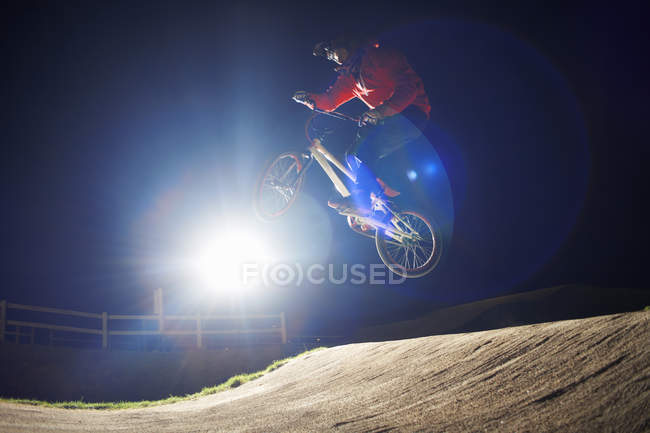 BMX-ciclista saltando la sua moto durante la notte — Foto stock
