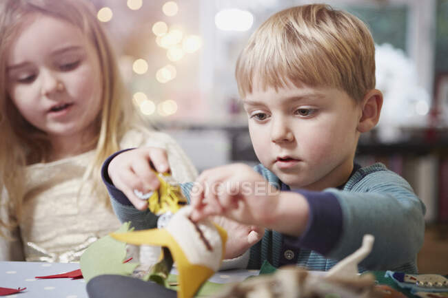 Young brother and sister crafting at kitchen table — Stock Photo
