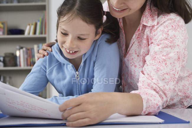 Mãe ajudando pequena filha com lição de casa — Fotografia de Stock