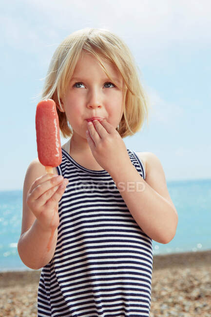 Criança com os dedos no lábio segurando gelo alegre — Fotografia de Stock