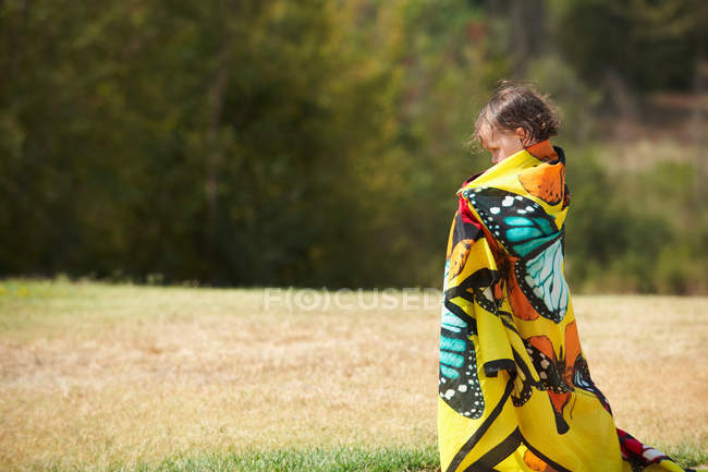 Девушка завернутая в красочное полотенце на открытом воздухе — стоковое фото