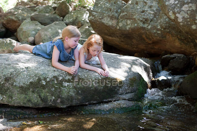 Дівчата, що лежать на скелі біля річки. — стокове фото