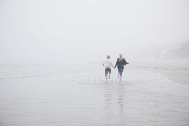 Couple courant sur la plage — Photo de stock