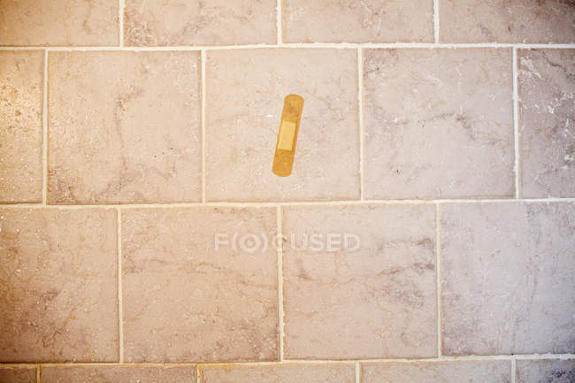 Adhesive plaster on tiled floor, top view — Stock Photo