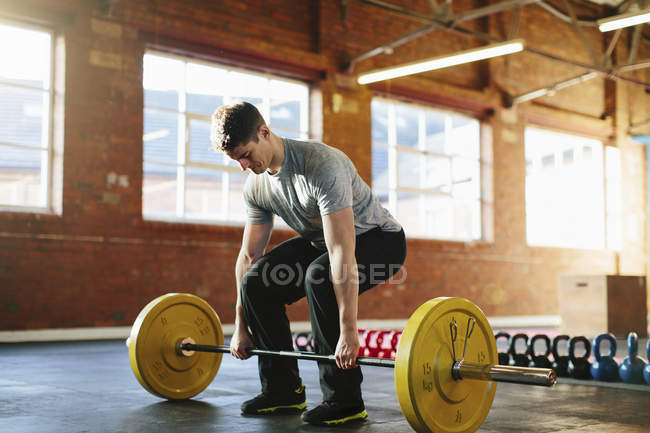 Mid adult athletic man lifting weights in gym interior — Stock Photo
