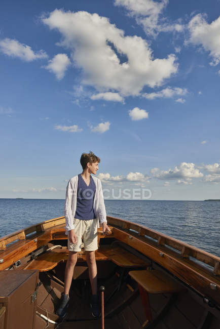 Хлопчик-підліток стоїть на човні, дивлячись далеко — стокове фото