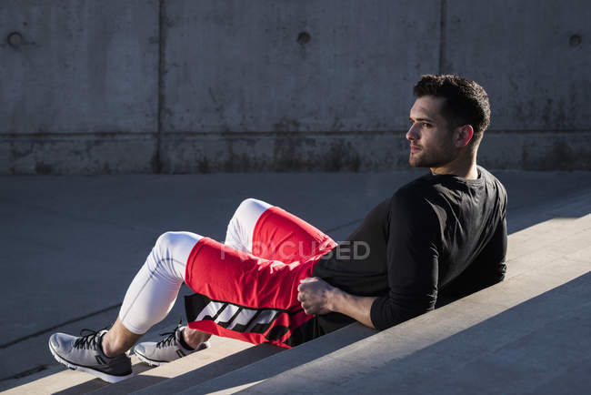 Young man training, taking a break on city stairs — Stock Photo