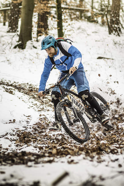 Jovem motociclista de montanha do sexo masculino em excesso de neve coberto trilha florestal — Fotografia de Stock