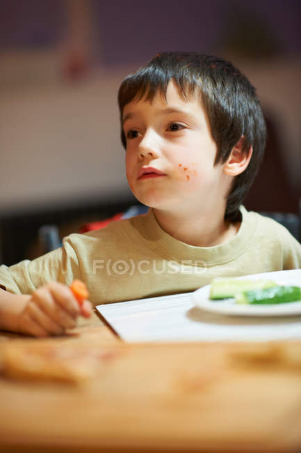 Мальчик ест за столом — стоковое фото