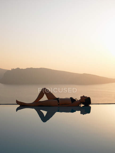 Mulher deitada na borda de uma piscina — Fotografia de Stock