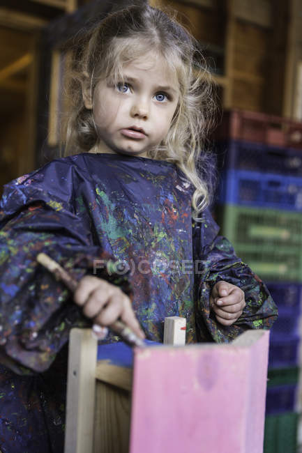 Bambina in abbigliamento protettivo pittura casa di legno — Foto stock