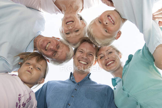 View from below of family in a huddle looking down at camera smiling — Stock Photo