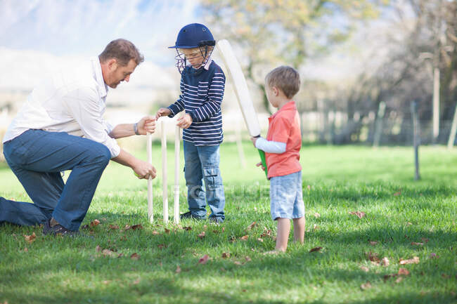 Father and sons preparing stumps for cricket — Stock Photo