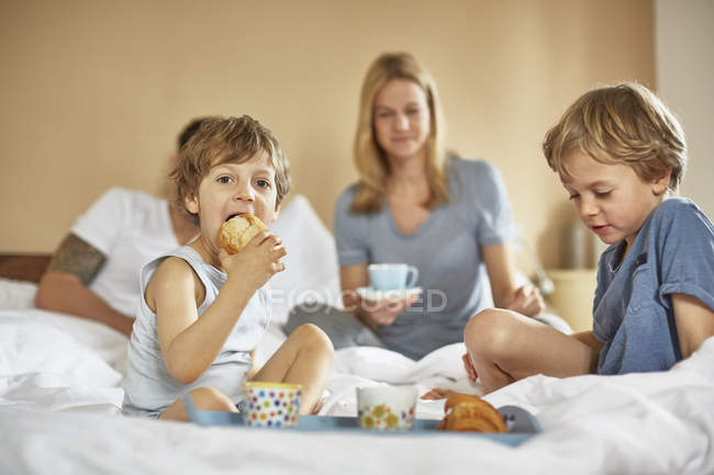 Garçons prenant le petit déjeuner dans le lit des parents — Photo de stock