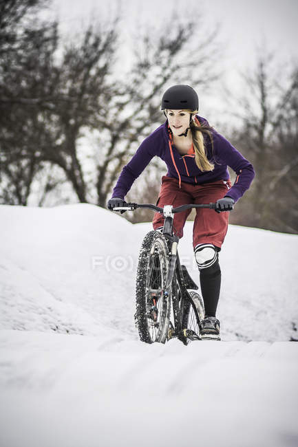 Metà adulto femmina mountain bike lotta per cavalcare attraverso la neve — Foto stock