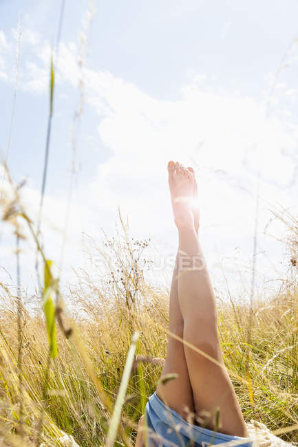 Young womans bare legs in field of long grass — Stock Photo