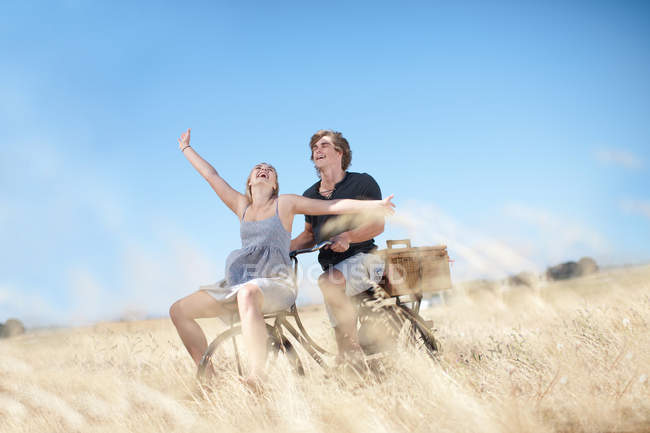 Couple riding bicycle in tall grass — Stock Photo