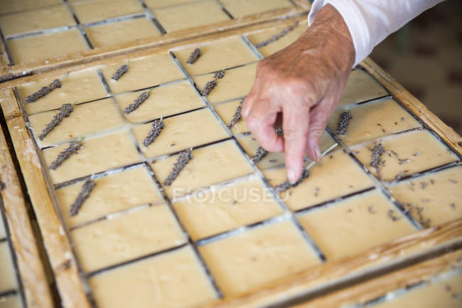 Female hand applying dried lavender to soap bars in handmade soap workshop — Stock Photo