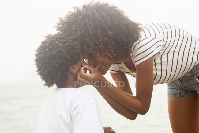 Portrait of young woman touching sons cheeks on Ipanema beach, Rio De Janeiro, Brazil — Stock Photo