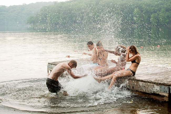 Mid adult man splashing friends in lake — Stock Photo