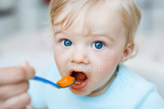 Bebê sendo alimentado olhando para o espectador — Fotografia de Stock
