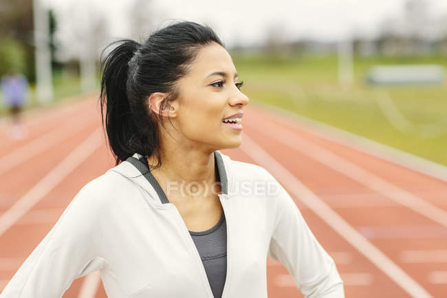 Portrait of young girl on running track, looking away, smiling — Stock Photo