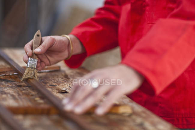 Carpinteiro mãos envernizando madeira com escova — Fotografia de Stock