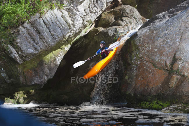 Homem adulto médio caiaque rio abaixo cachoeira — Fotografia de Stock